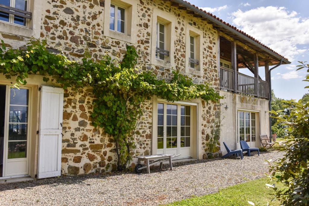 une maison en pierre avec une terrasse couverte et des chaises à l'extérieur dans l'établissement Gîte de Peyrefitte, à Lescure