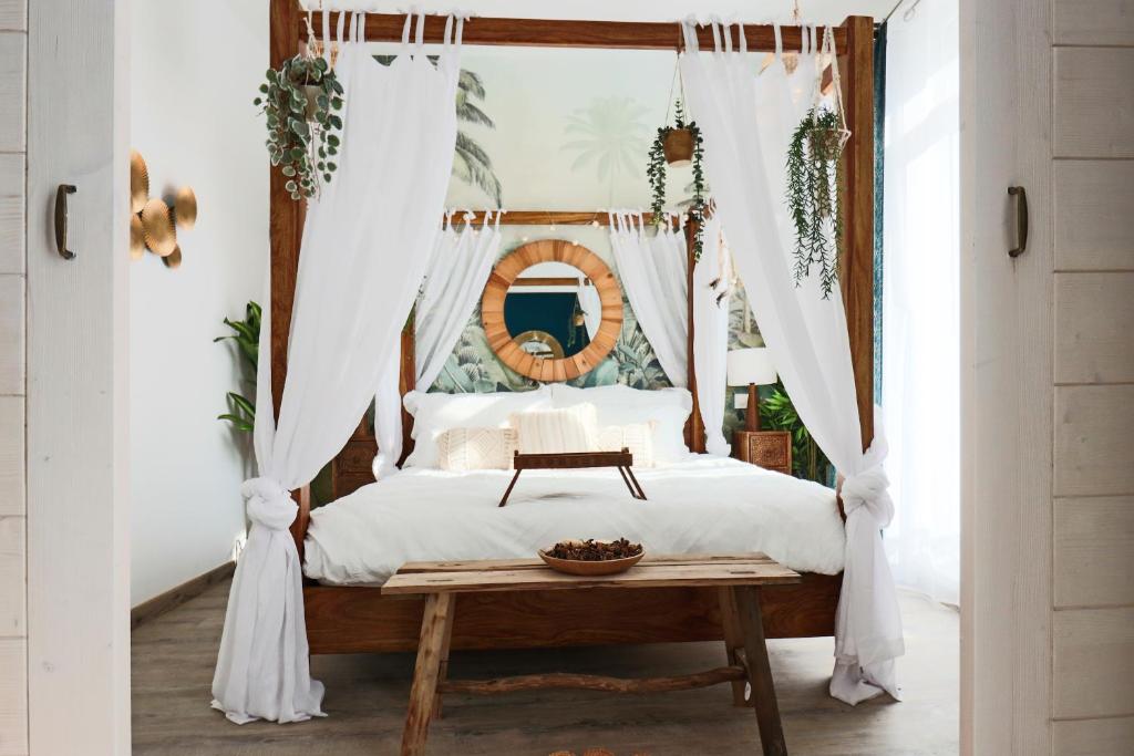 - une chambre avec un lit à baldaquin et une table dans l'établissement Superbe Suite Bali – Écran cinéma – Clim – Béziers, à Béziers