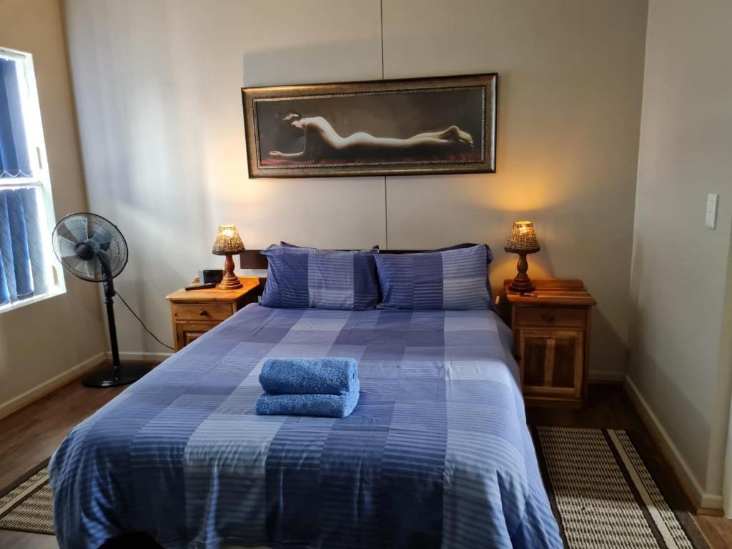 a bedroom with a blue bed with two blue towels on it at Point Village Accommodation - Estoril 26 in Mossel Bay