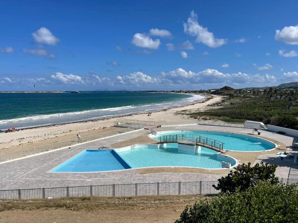 two swimming pools in front of a beach at Studio 03 vue mer Orient Bay in Orient Bay