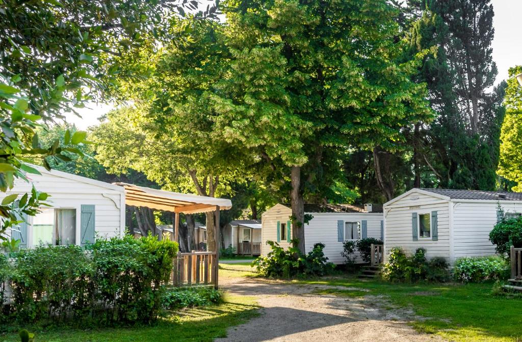 a row of white cottages with a tree at Camping les Avignon - la Laune in Villeneuve-lès-Avignon