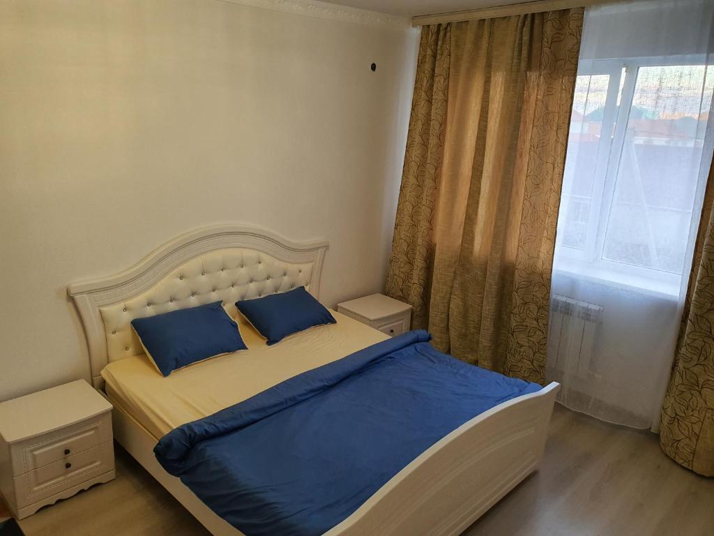 ein Schlafzimmer mit einem Bett mit blauen Kissen und einem Fenster in der Unterkunft 2-ух комнатная квартира Юнис Сити г.Актобе in Aqtöbe