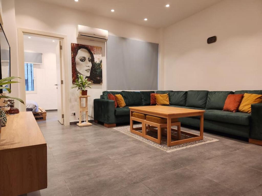 uma sala de estar com um sofá verde e uma mesa em Charming 2BR Gemayze em Beirute