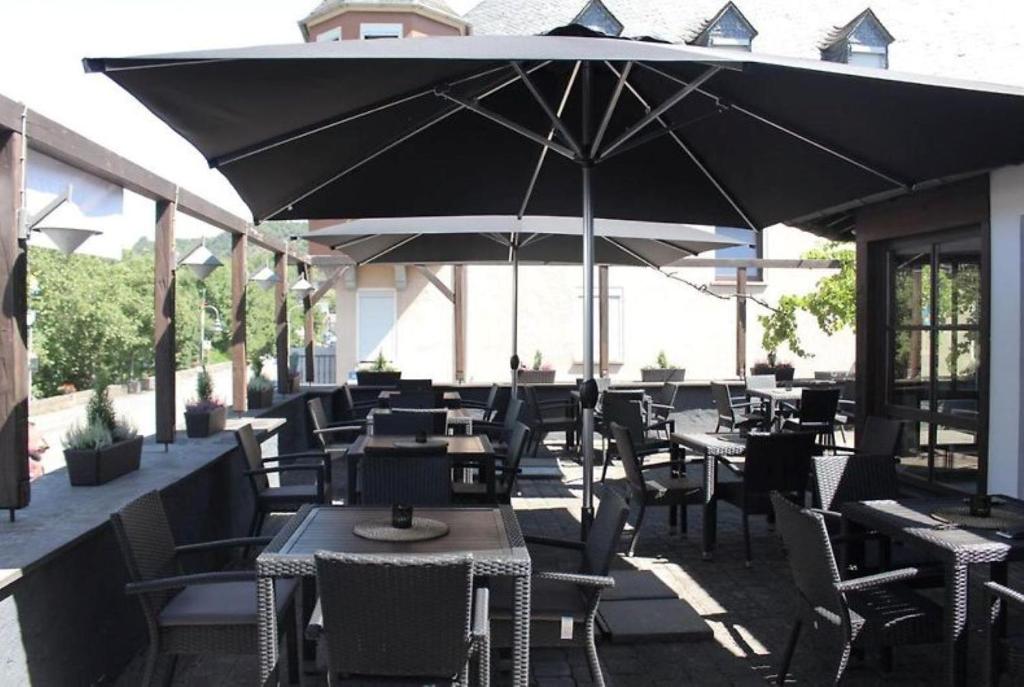 NiederfellにあるB3 Hotelのテーブルと椅子、傘が備わるレストラン