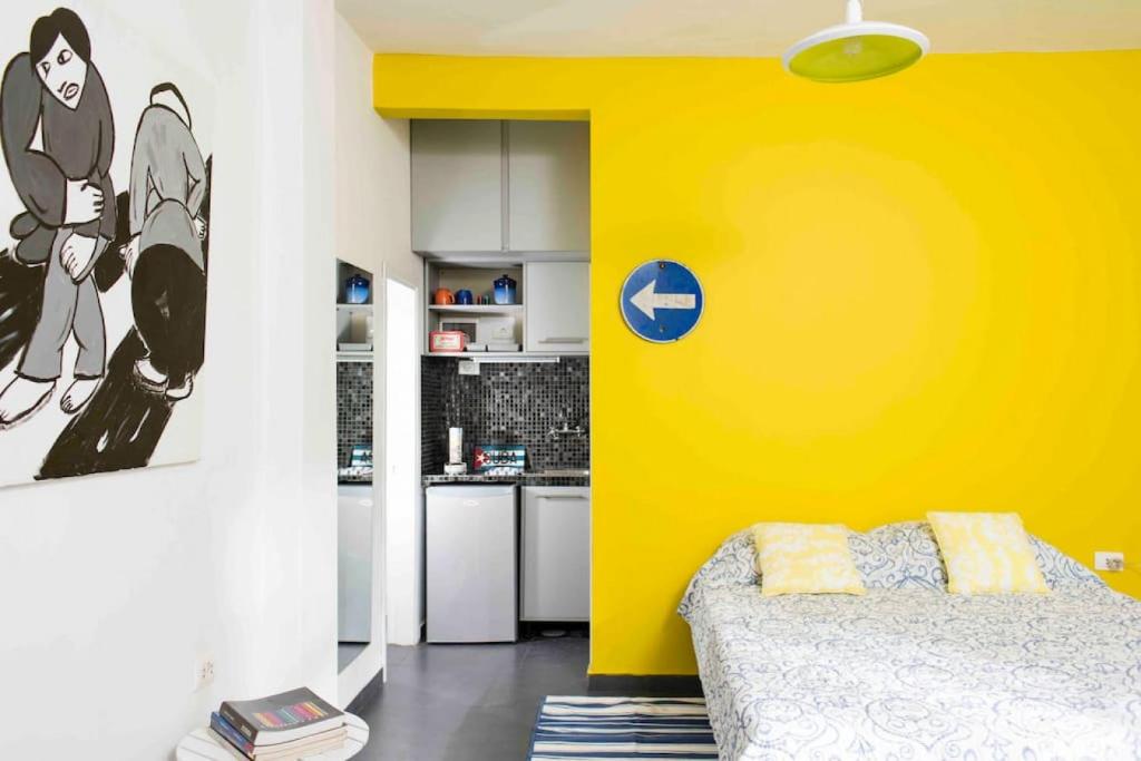 een gele kamer met een bed en een keuken bij Cozy Studio w Yard and Rooftop in Badawi in Beiroet