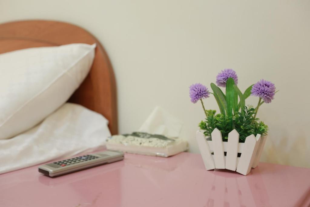 una mesa con mando a distancia y un jarrón con flores púrpuras en Good Sleep B&B en Ruifang