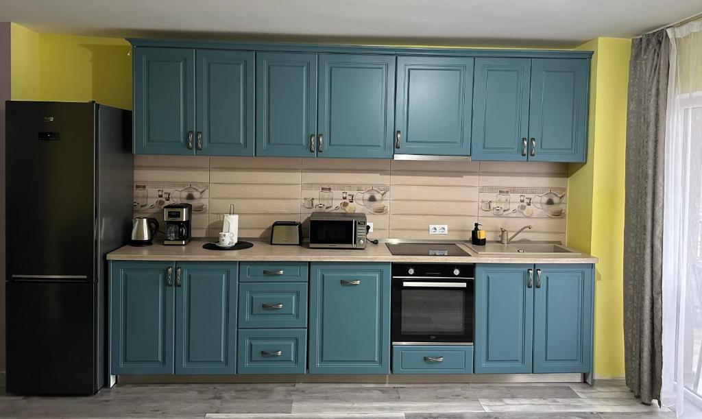 a kitchen with blue cabinets and a black refrigerator at Kiwi apartment in Bistriţa
