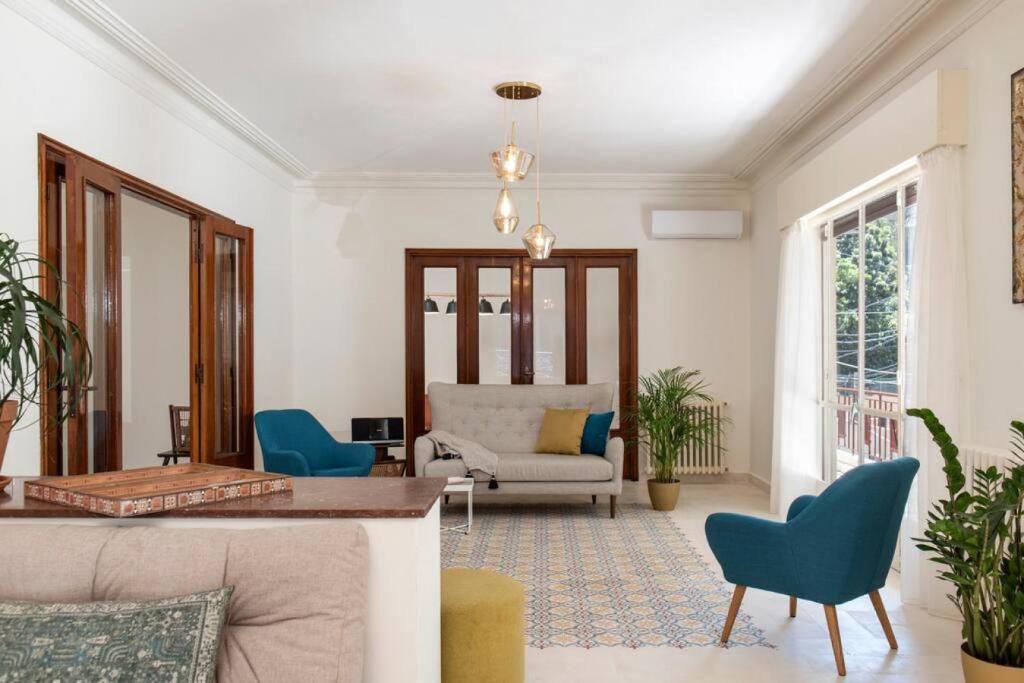 Mauds Elegant Cocoon at Monot في بيروت: غرفة معيشة مع كراسي زرقاء وأريكة
