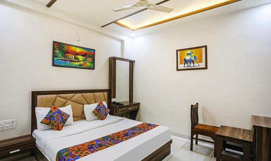 a bedroom with a bed and a desk in it at FabHotel The Crown in Tājganj