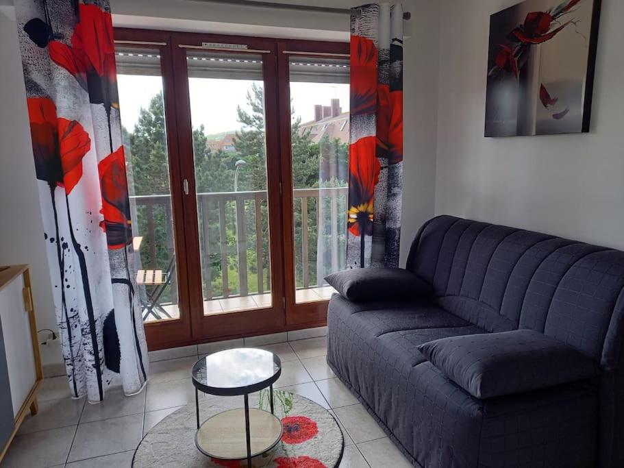 un salon avec un canapé et une fenêtre dans l'établissement Appartement 50 m de la mer proche Deauville, à Villers-sur-Mer