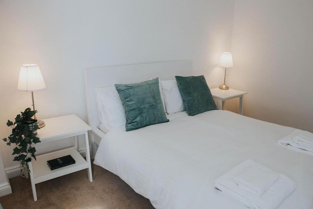 a bedroom with a white bed with green pillows at A 3 bedroom apartment with parking in central Kingsbridge in Kingsbridge