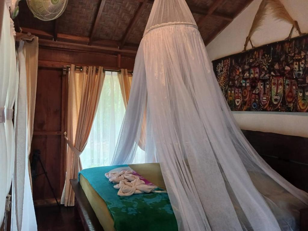 a bed with a mosquito net in a room at Tropical Jungle Hut in Bukit Lawang