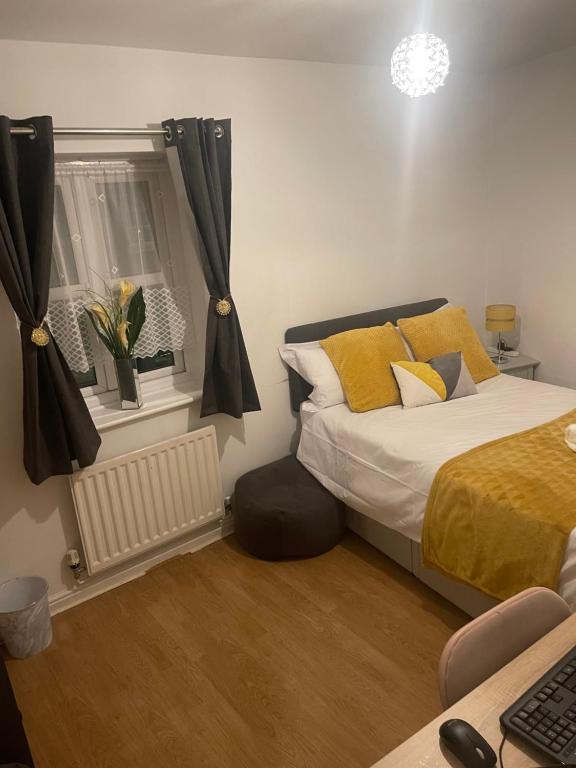 Un dormitorio con una cama con almohadas amarillas y una ventana. en Angels Pad, en Dagenham