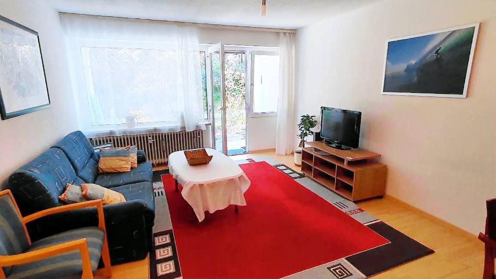 - un salon avec un canapé bleu et un tapis rouge dans l'établissement Ferienwohnung Ünal, à Prien am Chiemsee