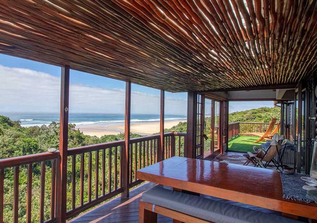 Un balcón con mesa y vista al mar. en Villa Mtati, en Port Alfred