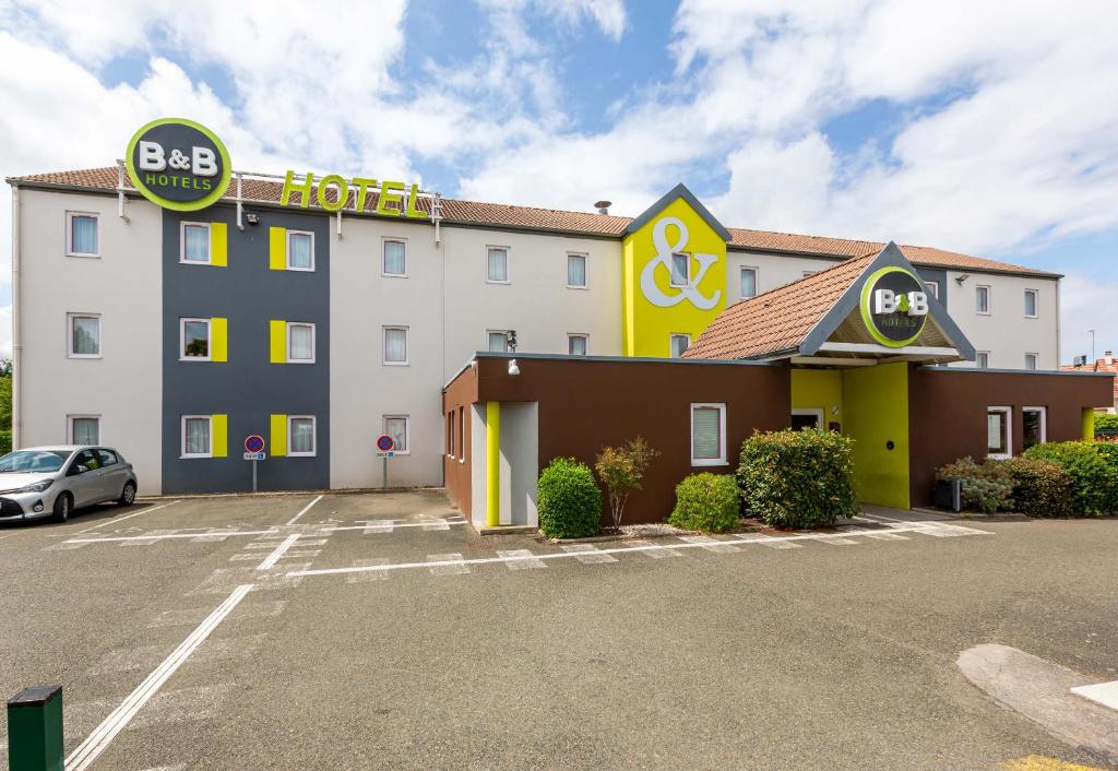 ein Gebäude mit einem Hotelschild auf einem Parkplatz in der Unterkunft B&B HOTEL CHARTRES Le Coudray in Chartres