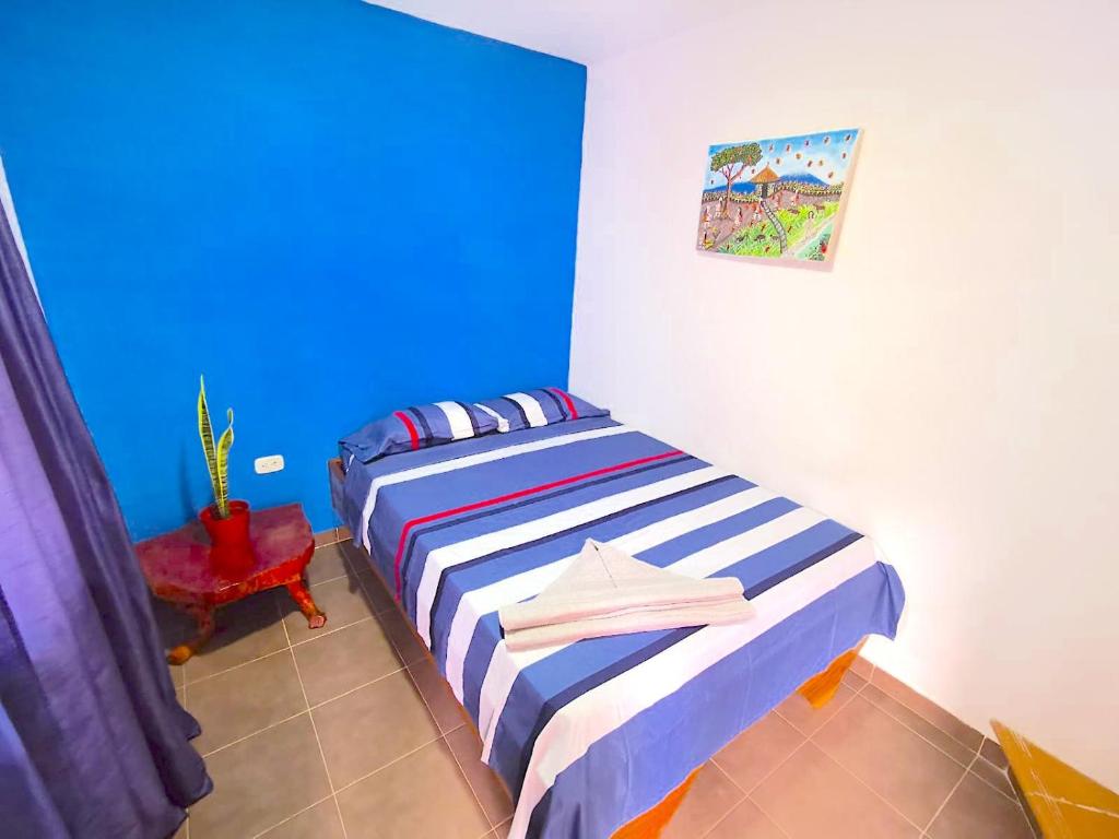 um quarto com uma cama com uma parede azul em Central Habitación en Minca em Minca