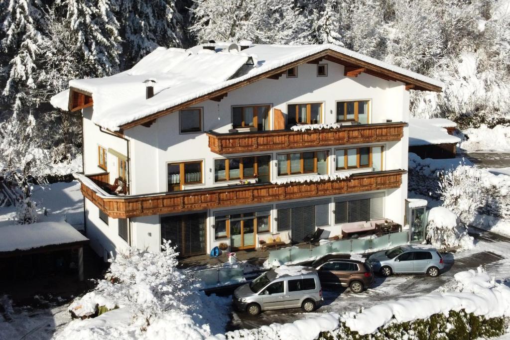 a house with cars parked in front of it in the snow at Apart Dahuam in Aschau