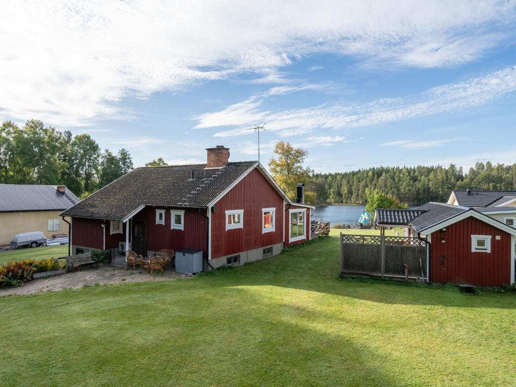 una gran casa roja con un patio y un lago en Chalet Toltorp - SDM100 by Interhome en Katrineholm