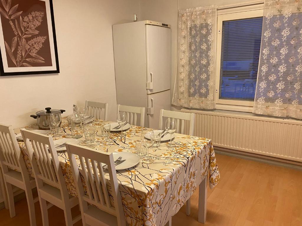 a dining room with a table with chairs and a refrigerator at Apartment MUMMOLA in Rovaniemi