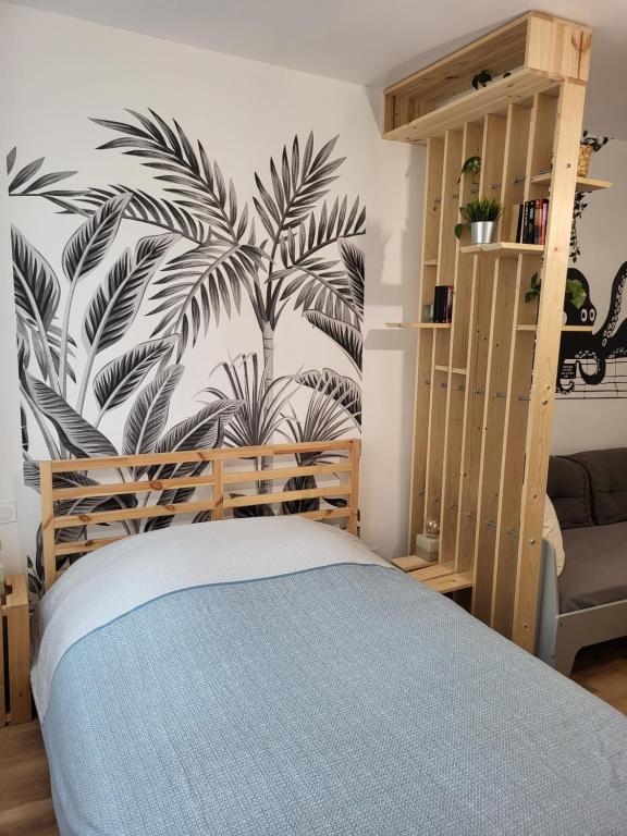 - une chambre avec un lit orné d'une fresque murale représentant un palmier dans l'établissement Le Lavoir - Studio centre ancien sur placette, à Toulon