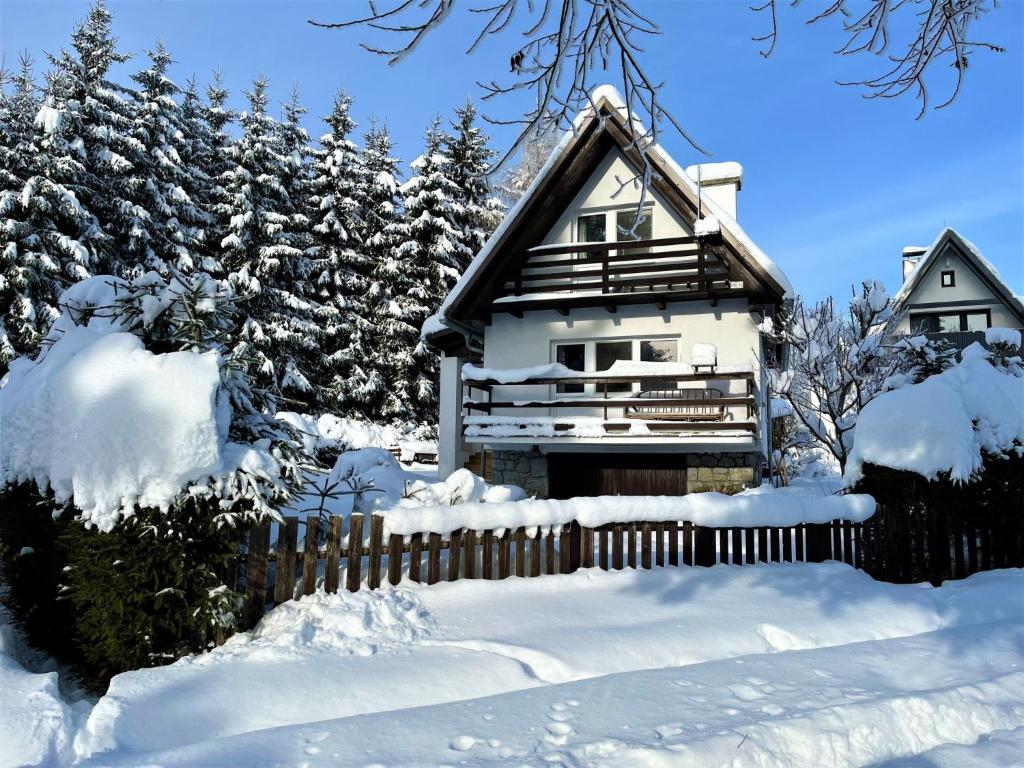 a house covered in snow next to a fence at Holiday Home Hůrka by Interhome in Horní Planá
