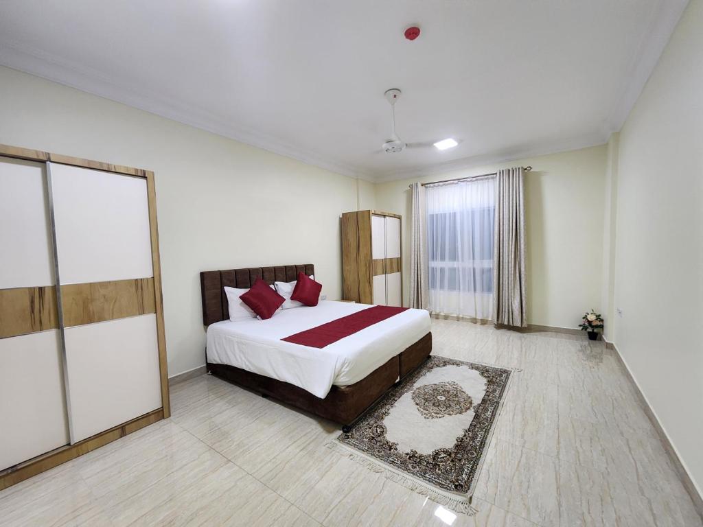 a bedroom with a large bed with red pillows at Sohar Hotel - فندق صحار in Sohar