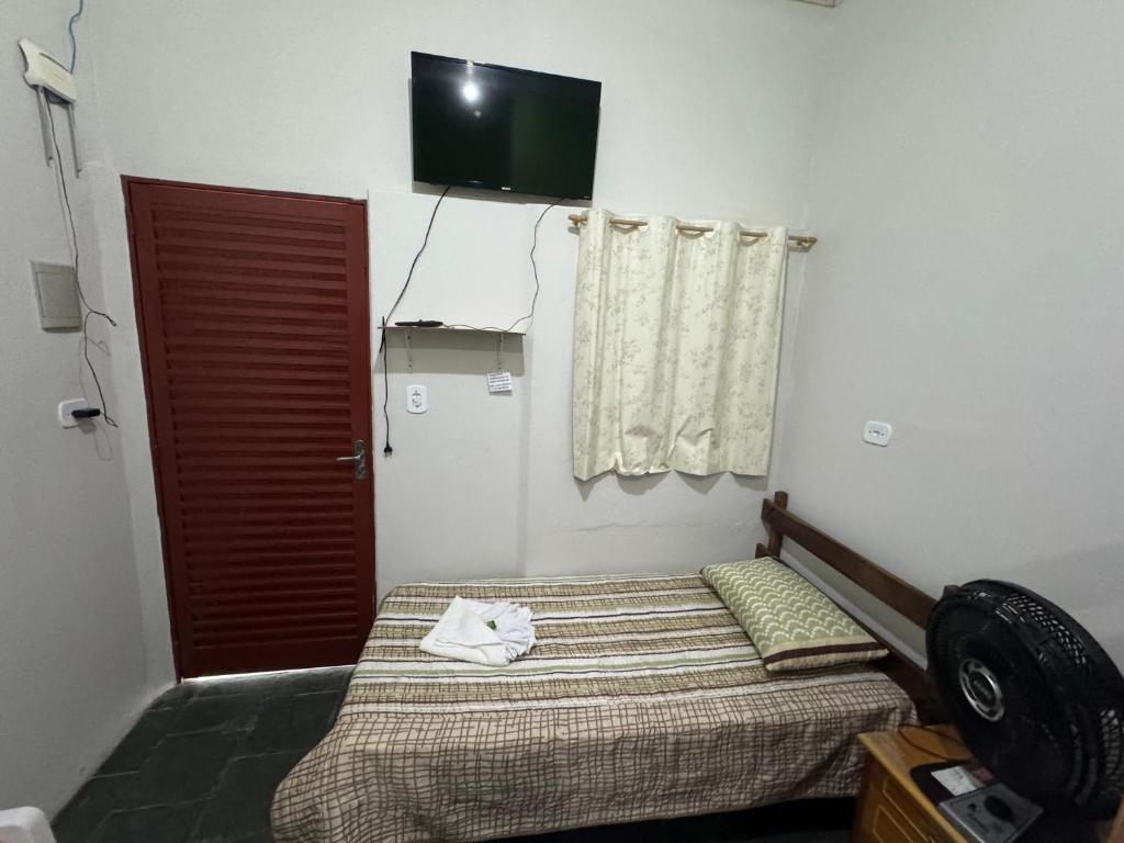 a bedroom with a bed and a television on the wall at Quarto Central in Guararema
