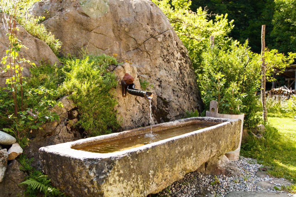 una fuente de agua de piedra en medio de un jardín en Ferienwohnung Hinterreiter en Ruhpolding
