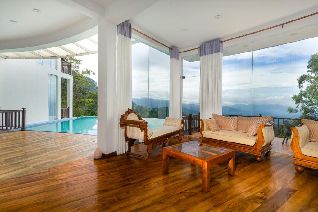 uma sala de estar com pisos em madeira e janelas de vidro em Villa Vajrapani em Kandy