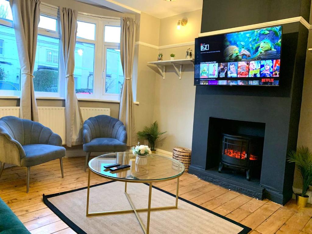 a living room with a fireplace with a tv above it at Cosy 3 bed house with FREE Parking near Kingston Thames in Malden
