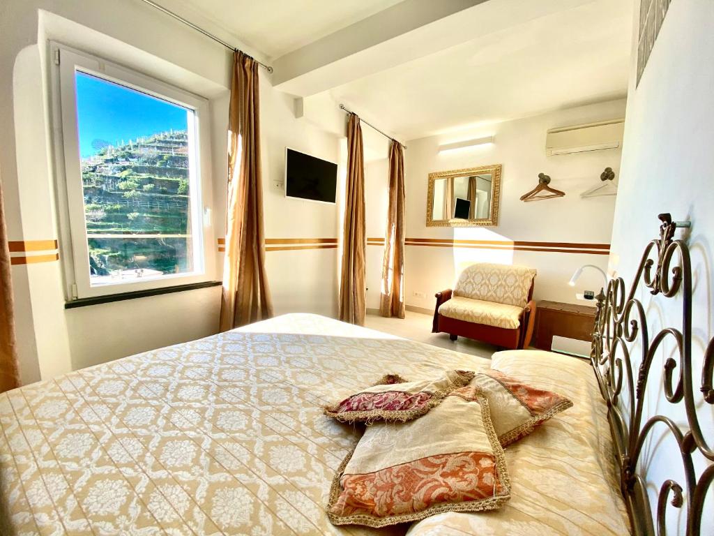 1 dormitorio con 1 cama con ventana y silla en The Manarola Main Plaza, en Manarola