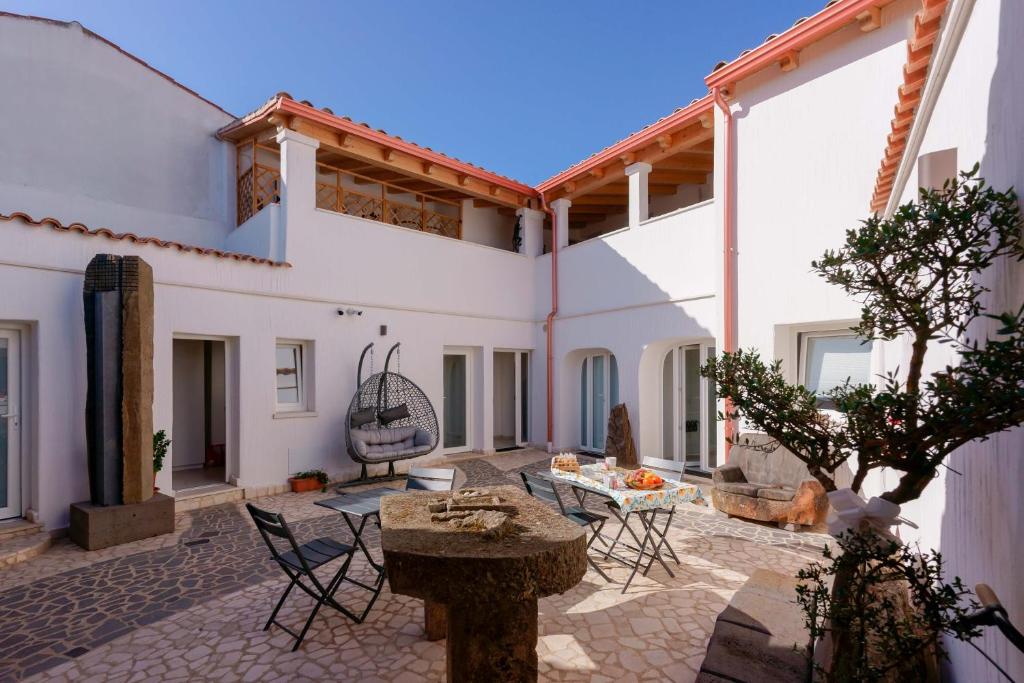 a patio with chairs and a table and a building at TS ROOMS - Guest House Sciola in San Sperate