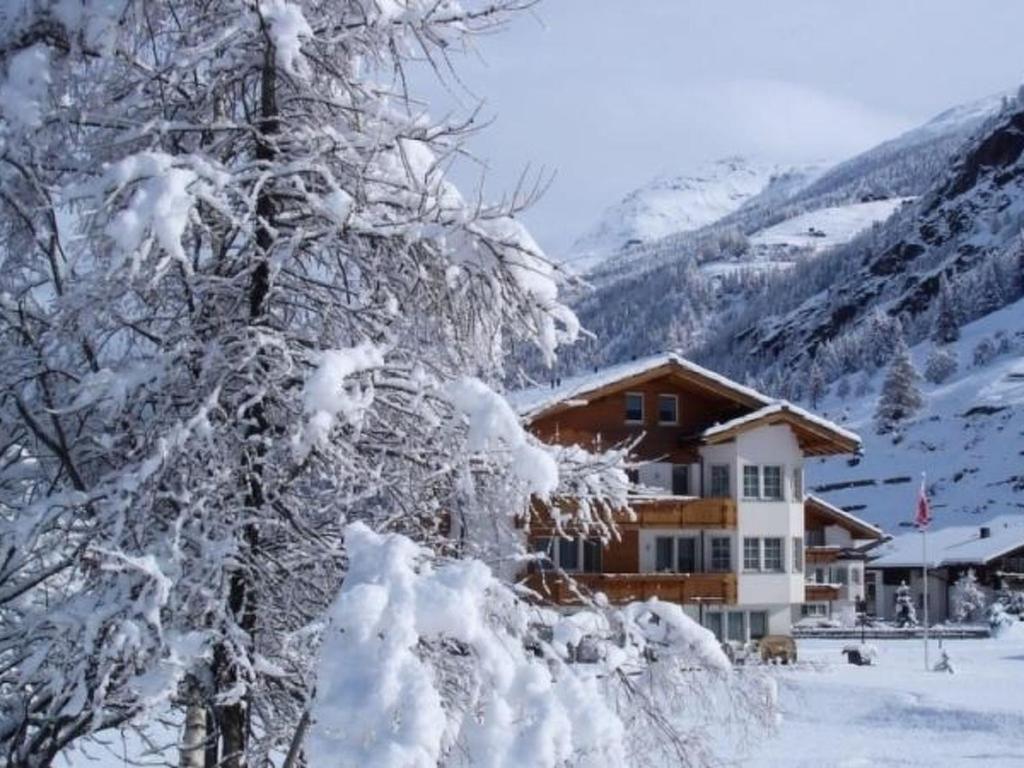 a snow covered tree in front of a building at Apartment Amaryllis by Interhome in Saas-Grund