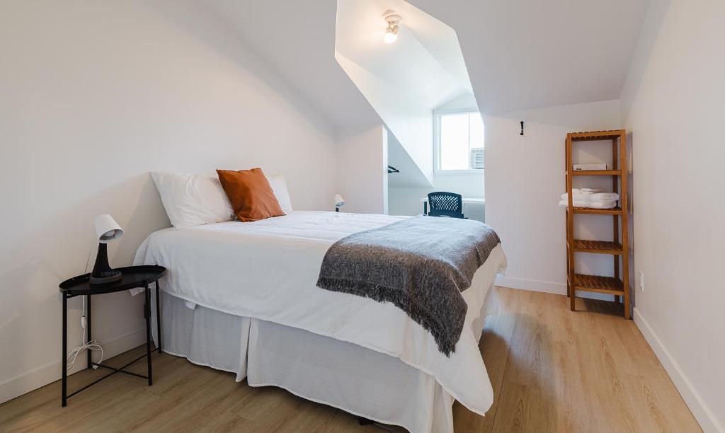 1 dormitorio blanco con 1 cama y escalera en Villa de Brome en Lac-Brome