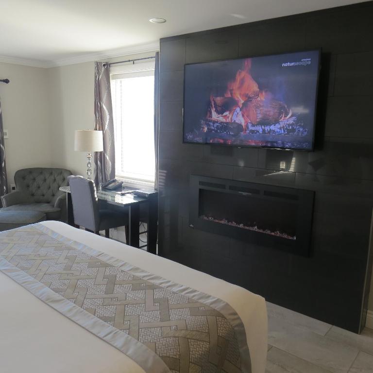 a bedroom with a fireplace and a tv on a wall at Dockside Suites in Digby