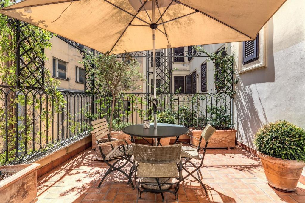 een patio met een tafel en stoelen en een parasol bij Via Napoli Apartments in Rome