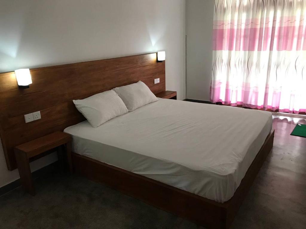 a bedroom with a large bed with a wooden headboard at Midira Villa in Galle