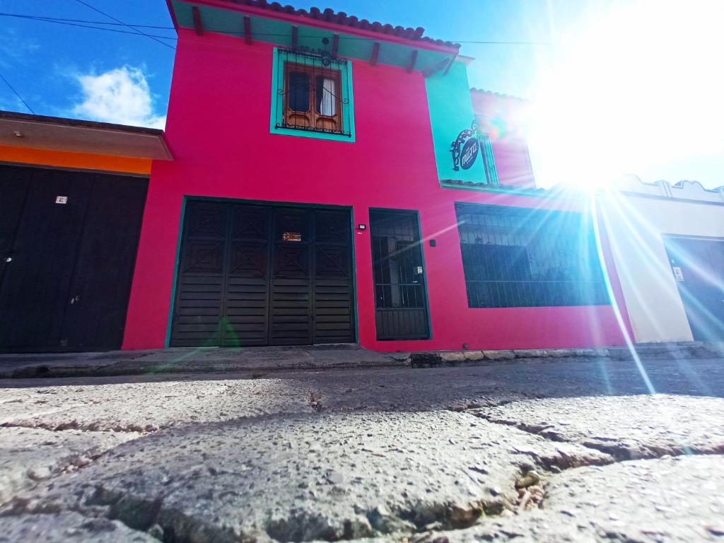 un edificio rosa con el sol en el cielo en Kaza Muta en San Cristóbal de Las Casas