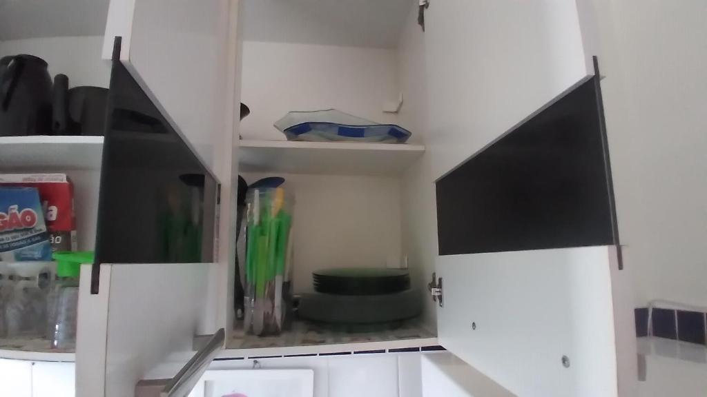 a white cabinet with a tv in a kitchen at Condomínio Pousada Amarela 100 metros da Praia in Iguaba Grande