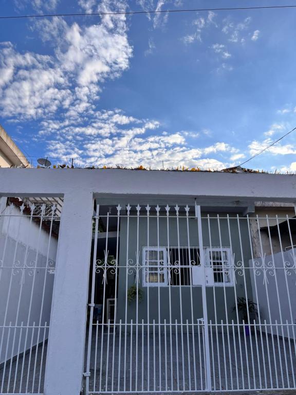 Uma casa branca com um portão à frente. em Casa Bela na Praia Grande