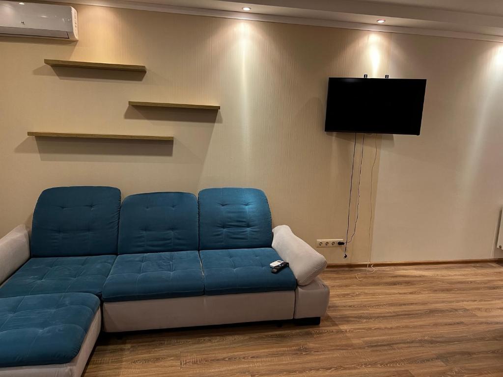 a blue couch in a room with a flat screen tv at VIP апартаменти ЦЕНТР in Rivne