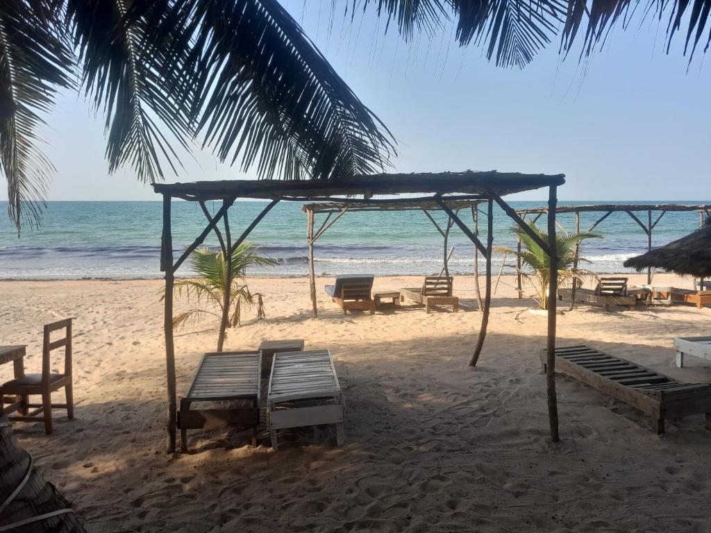 a group of benches on a beach with the ocean at Smile Gambia Beach Bar in Brufut