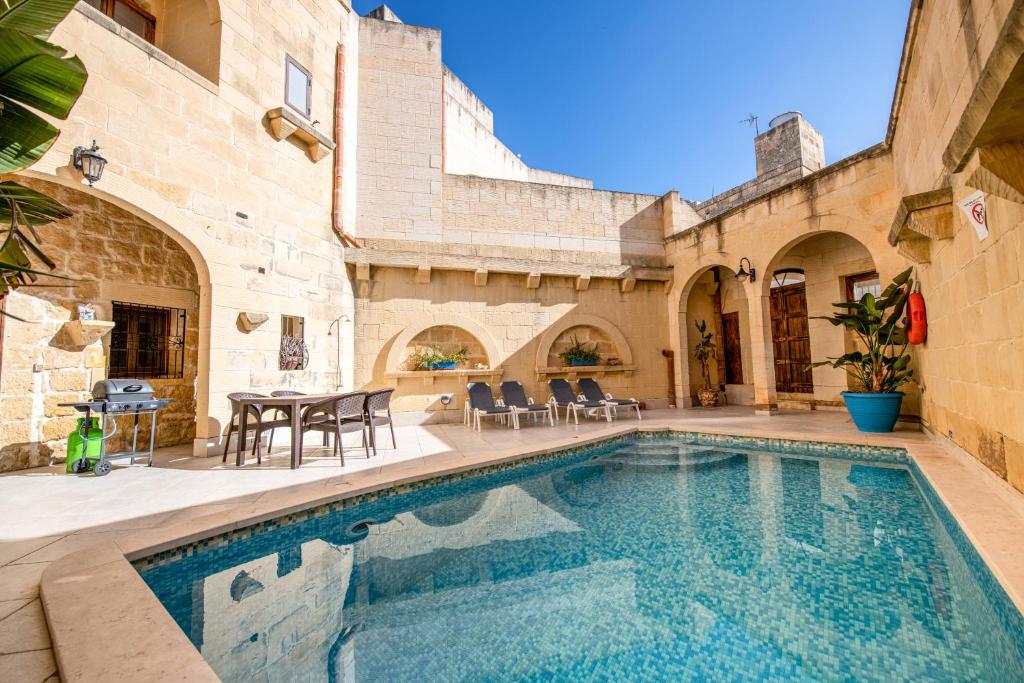 a swimming pool in a courtyard with a house at 4 Bedroom Farmhouse with Large Private Pool in Xewkija