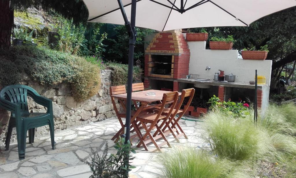 a table and chairs under an umbrella in a garden at Meublé Bulgarana - 4 pers in Bourg-Argental