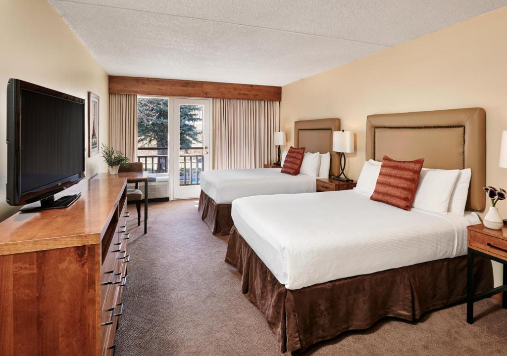 a hotel room with two beds and a flat screen tv at The Inn at Aspen in Aspen