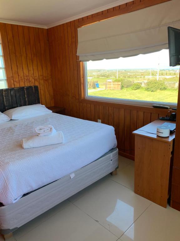 a bedroom with a bed and a television and a window at Cabañas Patagonia Encantada in Puerto Natales