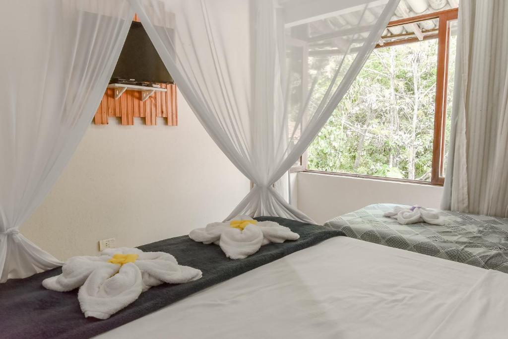 a bedroom with towels on a bed with a window at Pousada Sonhos de Praia, Fácil Acesso a Praia, Rua Mucugê e Beco das Cores in Arraial d'Ajuda