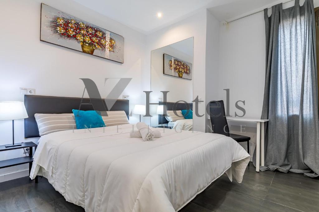 Un dormitorio con una gran cama blanca y un escritorio. en AYZ Ulises - Auto check-in property, en Madrid