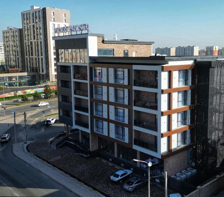 un bâtiment dans une ville avec un parking dans l'établissement Shymkent Park Hotel, à Chimkent